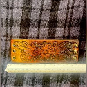 Handmade leather cuff with embossed floral design and 3snap closure.